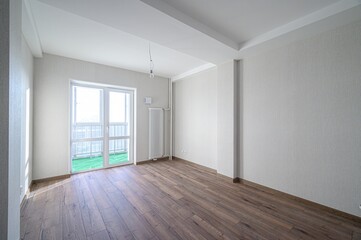 Bright, empty room with wood floors, white walls, and a balcony door. Minimalist design