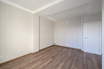 Empty room with brown wood floors, light wallpaper, white door ceiling. Bare bulb hanging