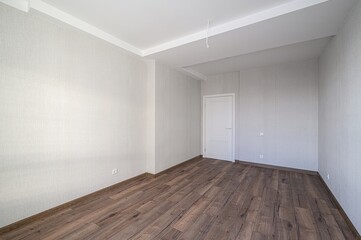 bright, empty room with light walls, dark wood flooring, a white door, and a white ceiling