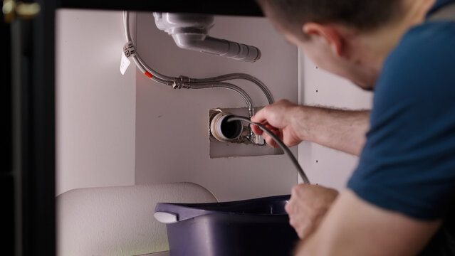 Plumber drill through clogged sink pipes with spring tube tool - Powered by Adobe