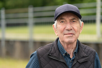 Happy senior man wearing cap and vest enjoying a spring day outside. Concept: life experience,...