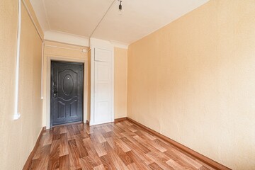 empty room with yellow walls, wood flooring, a black door, and a white closet. Bare bulb