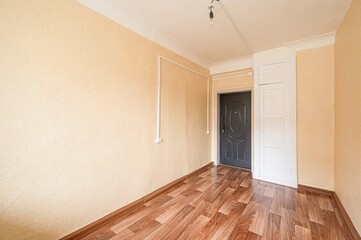empty room with yellow walls, wood flooring, a black door, and a white closet. Bare bulb