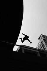Black and white photo of a man performing a parkour trick. Extreme sports photo.