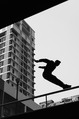Black and white photo of a man performing a parkour trick. Extreme sports photo.