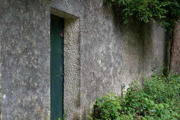 Textured concrete wall with a green door. Concept: architectural contrast, minimalism, urban design, raw beauty, industrial meets nature.