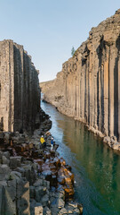 Visitors marvel at the striking basalt columns of Studlagil Canyon, nestled in Icelands scenic...