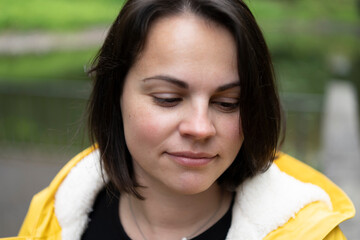 smiling woman in a yellow raincoat close-up in the forest. Concept: joy in nature, outdoor resilience, bright mood, connection with the wild, weatherproof happiness.