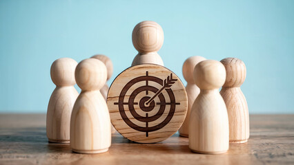 Wooden figures gathered around a wooden target with an arrow in the bullseye symbolizing shared goals and teamwork
