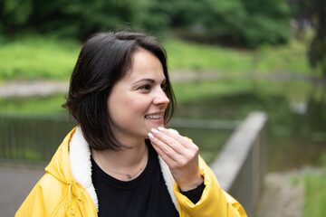 Smiling woman in a yellow raincoat close-up in the forest. Concept: joy in nature, outdoor...