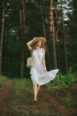 Tourist walking in forest wearing white dress and straw hat