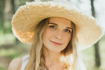Blonde woman wearing straw hat enjoying nature in summertime