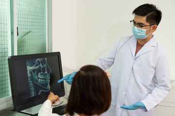 Dentist discusses dental X ray with patient in clinic