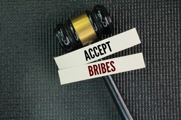 Judge's hammer and paper with the word accept bribes. agreeing to receive money or something...