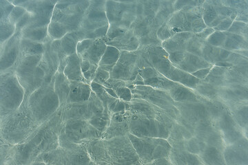 Texture of the sea water surface with small waves and sun reflections.