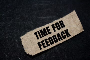 Time for feedback message written on ripped torn paper piece on black background. Conceptual time...