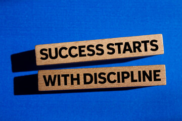 Success starts with discipline message written on wooden blocks on blue background. Conceptual...