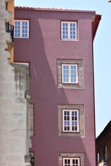 Pale purple multi-storey town house revealing stone wall around multi-pane windows. Location: Porto Portugal