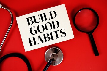 Build Good Habits text written on paper card with stethoscope on red background