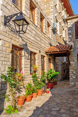 Traditional stone house with potted plants in sunlit alley of Ulcinj Old Town, Montenegro