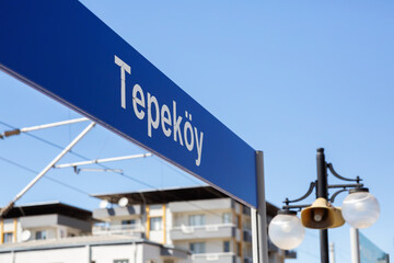Tepekoy train station sign with residential buildings in background on a sunny day in Izmir, Turkey