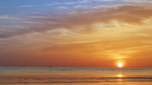 Golden sunset light glimmers across a softly rippling sea, viewed from ground level&mdash;distant boats linger near the horizon as warm reflections stretch over textured waves, capturing tranquil rhythm and