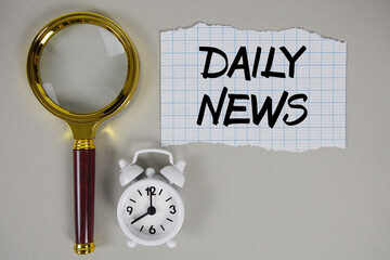 Daily News text written on paper with magnifying glass and alarm clock