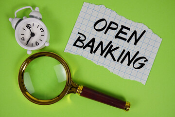 Open Banking text written on paper with magnifying glass and alarm clock