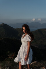 A beautiful girl in a sarafan walks in the mountains. Wind in her hair.