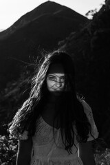 A beautiful girl in a sarafan walks in the mountains. Wind in her hair.