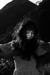 A beautiful girl in a sarafan walks in the mountains. Wind in her hair.