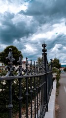 Fototapeta premium Ornate black iron fence against cloudy sky