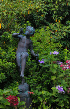 Garden statue of a child playing the flute surrounded by flowers