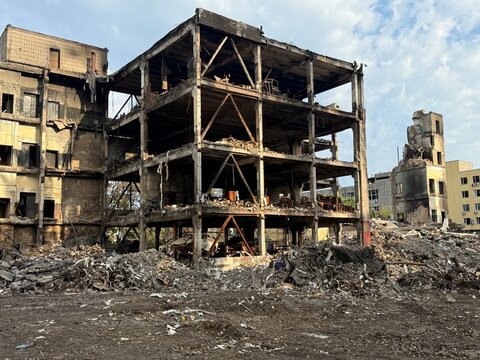This photo shows heavily damaged non-residential buildings in Kyiv, Ukraine, after a missile strike. Only the monolithic concrete frame remains, with walls completely destroyed. The scene depicts a po