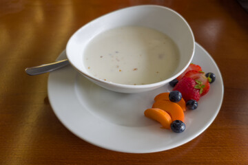 Breakfast of milk oatmeal served with fresh fruits and berries