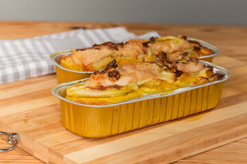 Potato casserole with chicken meat in foil containers, side view
