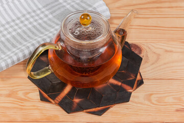 Steeped black tea in glass teapot on stand under hot
