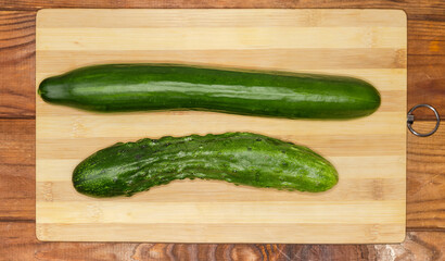 Long cucumbers of different varieties on cutting board, top view