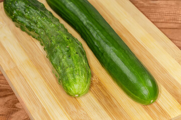 Long cucumbers of different varieties on cutting board, front view