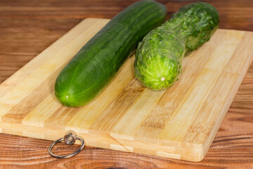 Long cucumbers of different varieties on cutting board, selective focus