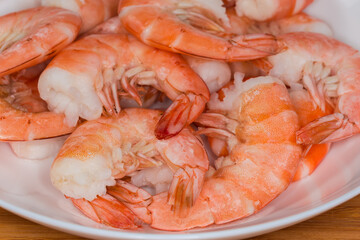 Boiled unshelled tails king prawns on dish, fragment close-up