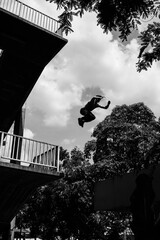 Black and white photo of a man performing a parkour trick. Extreme sports photo.