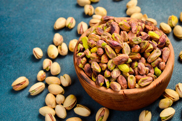 Shelled pistachio kernels in a wooden bowl. Close-up, side view.