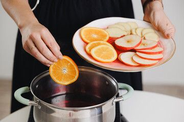 Woman cooking with fresh citrus mulled wine and apple slices