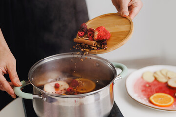 Preparing spiced berry and citrus infusion with cinnamon and clove mulled wine
