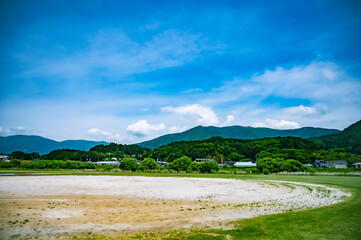 青空と山並みに囲まれた地方の野球グラウンド跡地（夏景色）