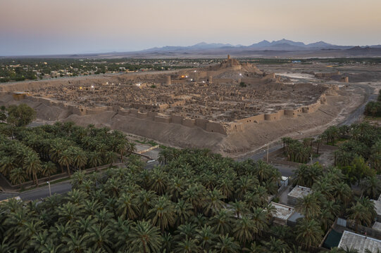 Aerial view of the ancient Arg-e Bam citadel glows with warm light against the cool desert backdrop, a testament to history, Bam, Kerman Province, Iran.