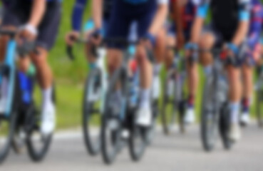 Naklejka premium Intentionally blurred group of many cyclists energetically pedaling their racing bikes during competitive road race
