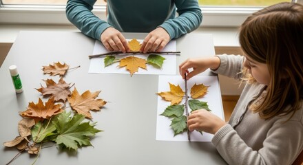 Children creating leaf art: young caucasian girl and boy crafting with autumn leaves