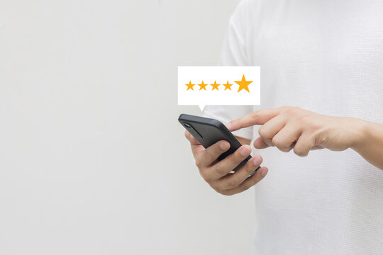 close up on customer man hand pressing on smartphone screen with gold five star rating feedback icon and press level three rank (good) for give score point to review the service business concept